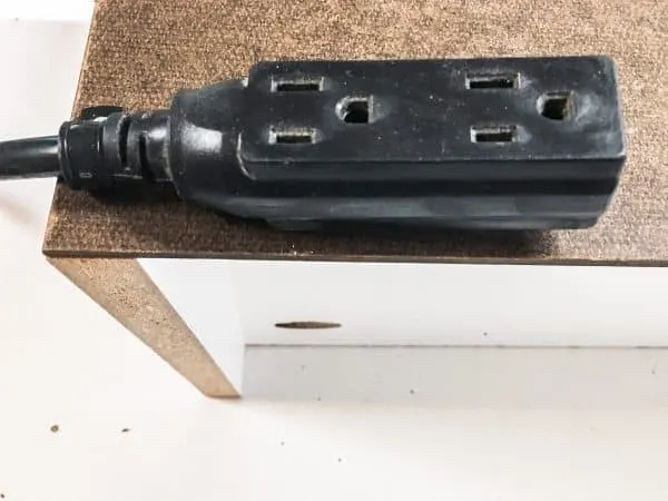 extension cord attached to the back of a cordless drill storage rack for battery chargers
