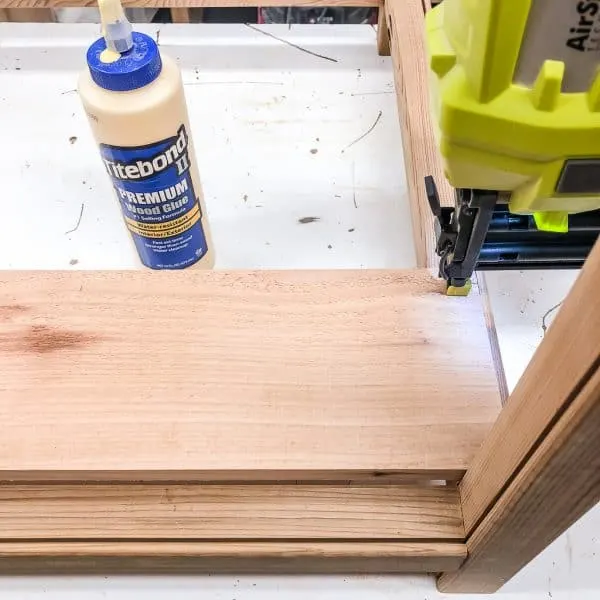 attaching bottom slats of modern planter box to frame with nail gun