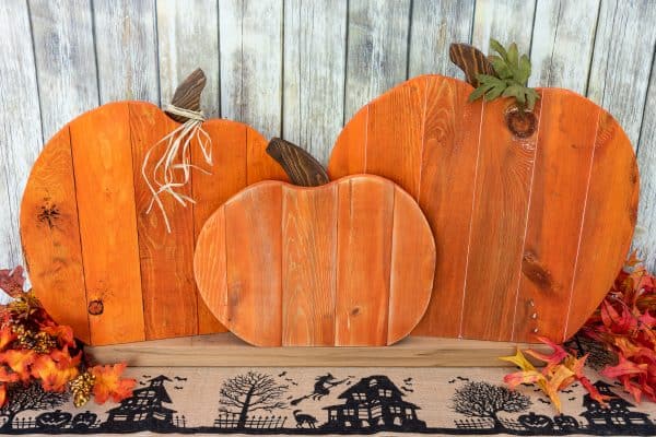 pumpkin pallet trio surrounded by fall leaves in front of a rustic background