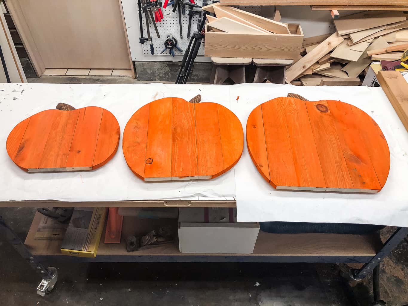 three pallet pumpkins set on a workbench to dry after applying orange wood dye