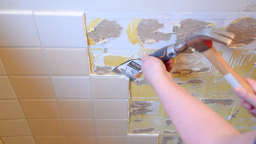 removing wall tiles with a scraper chisel and a hammer
