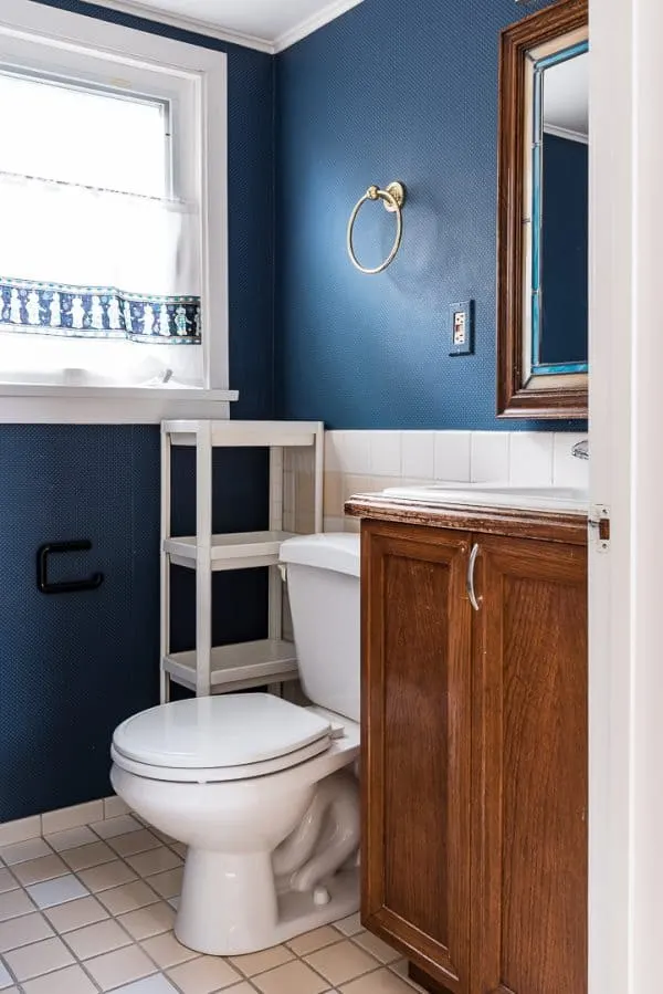 small half bathroom with blue wallpapered walls