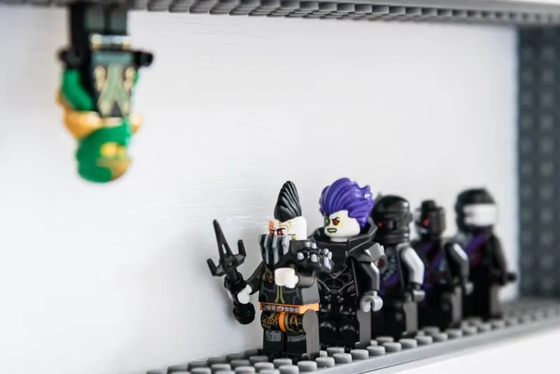 Lego minifigure hanging from top of DIY Lego minifigure display case shelf
