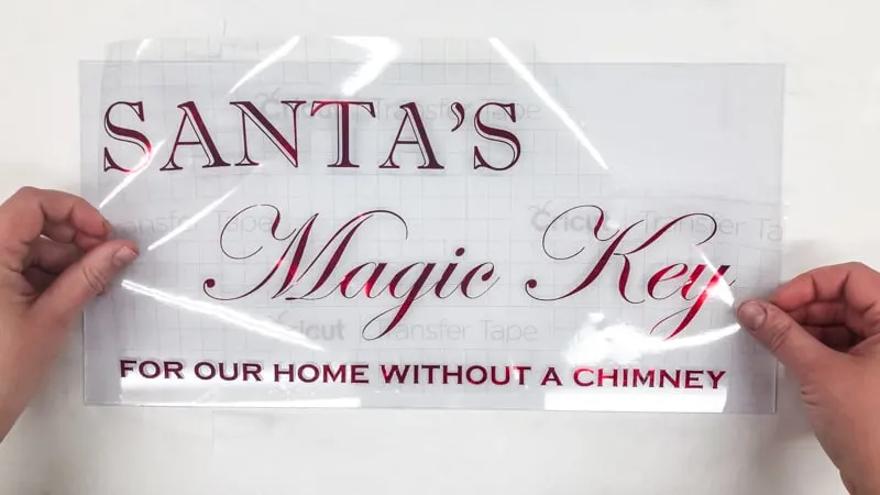 Applying Santa's Magic Key lettering to picture frame glass with transfer tape