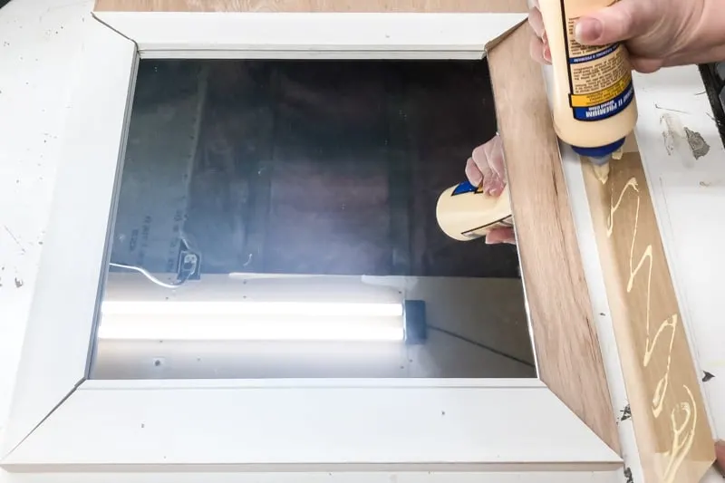 applying wood glue to the back of trim for entryway mirror