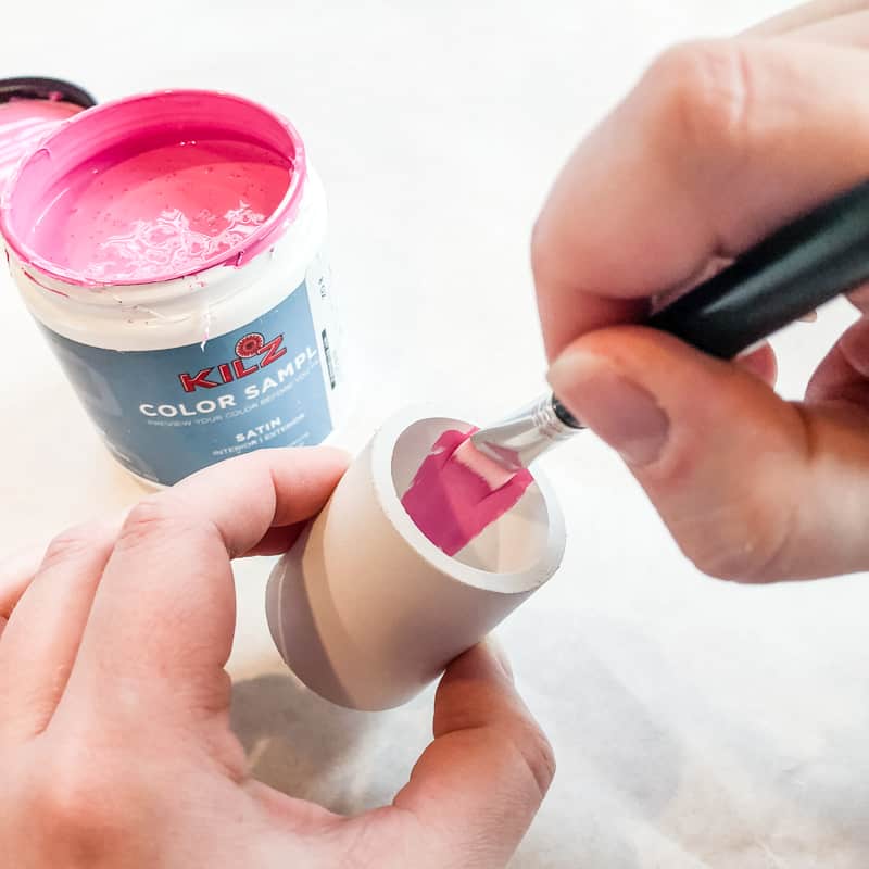 painting the inside of PVC pipe pieces bright pink with flat artist brush