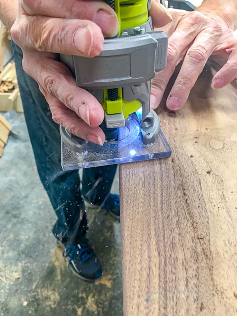 Palm router with ⅛" roundover bit trimming edge off of cutting board