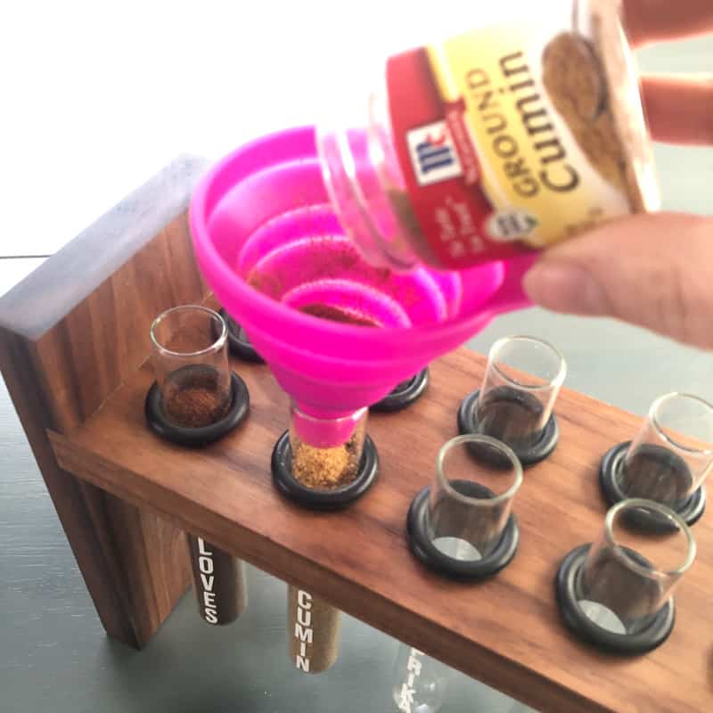 filling test tubes for DIY spice rack with pink funnel