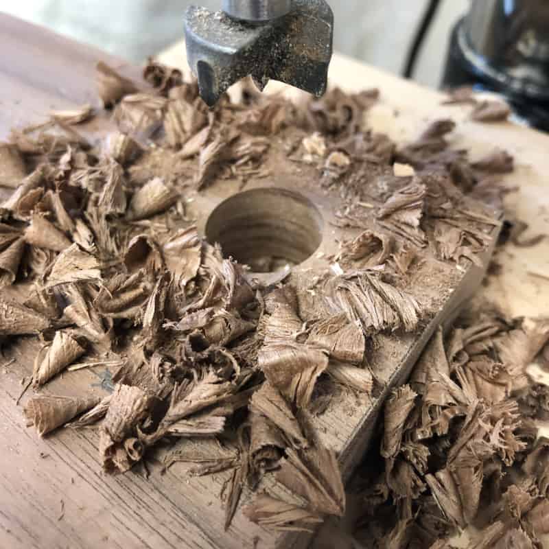 walnut wood shaving around hole drilled with forstner bit