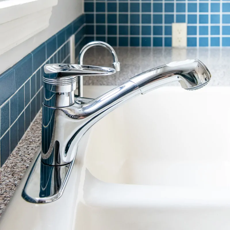 old kitchen faucet on almond colored sink with blue backsplash