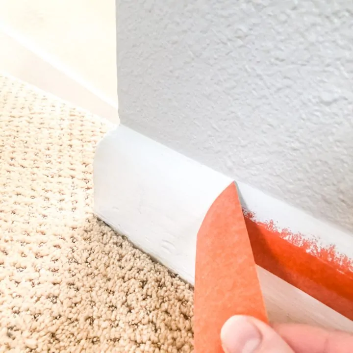 pulling away painter's tape on baseboards