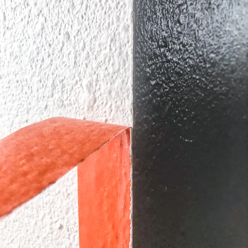 pulling away orange painter's tape to reveal clean paint line