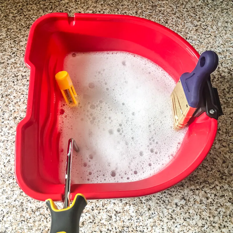 HANDy PRO pail filled with soapy water with paint brush bristles and roller submerged