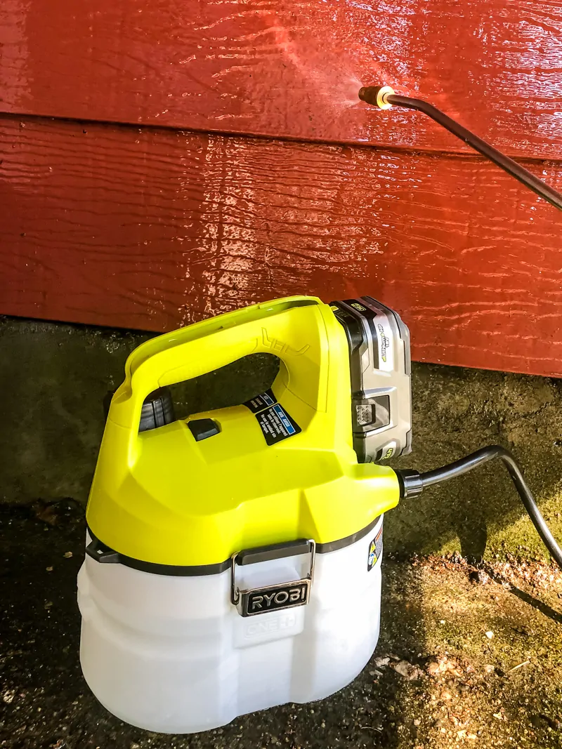 spraying TSP onto red aluminum siding with chemical sprayer