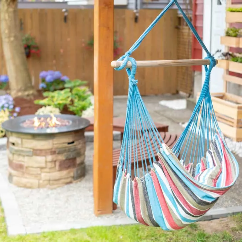 hammock hanging from deck with fire pit and gravel patio in the background