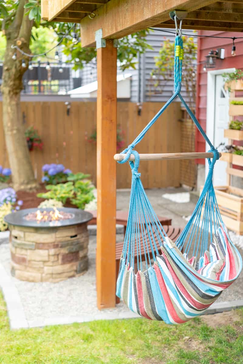 backyard with hammock and propane fire pit on pea gravel patio