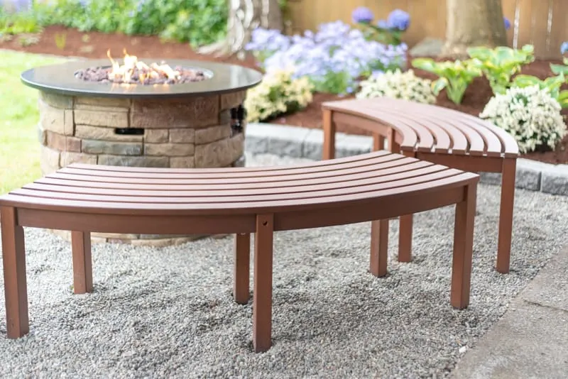 propane fire pit with curved benches on pea gravel patio