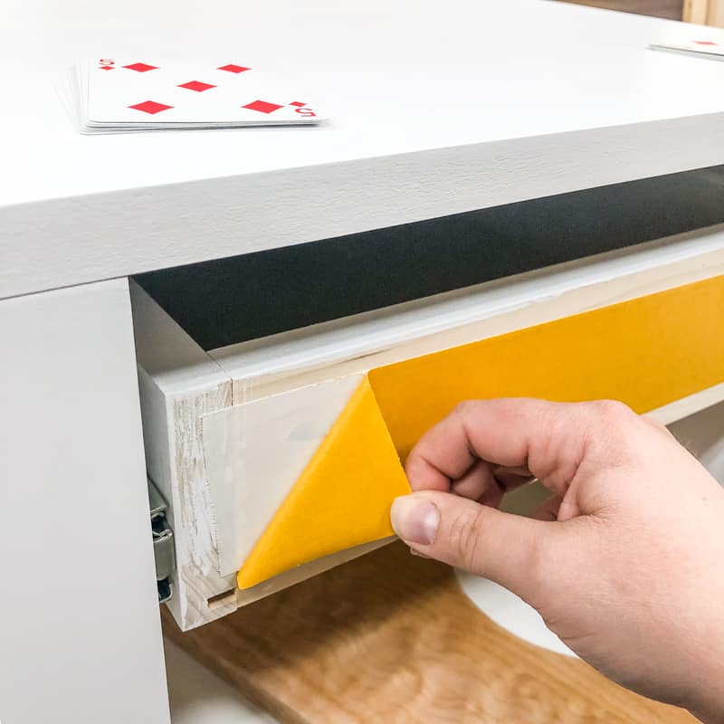 peeling off backing of double sided tape on front of the drawer box