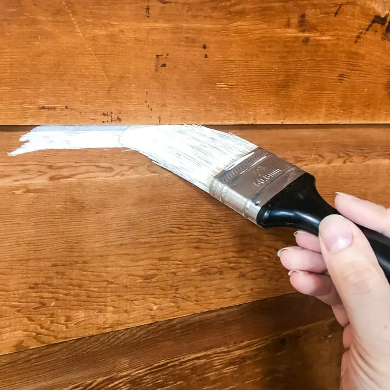 applying shellac-based primer to wood paneling with a paint brush