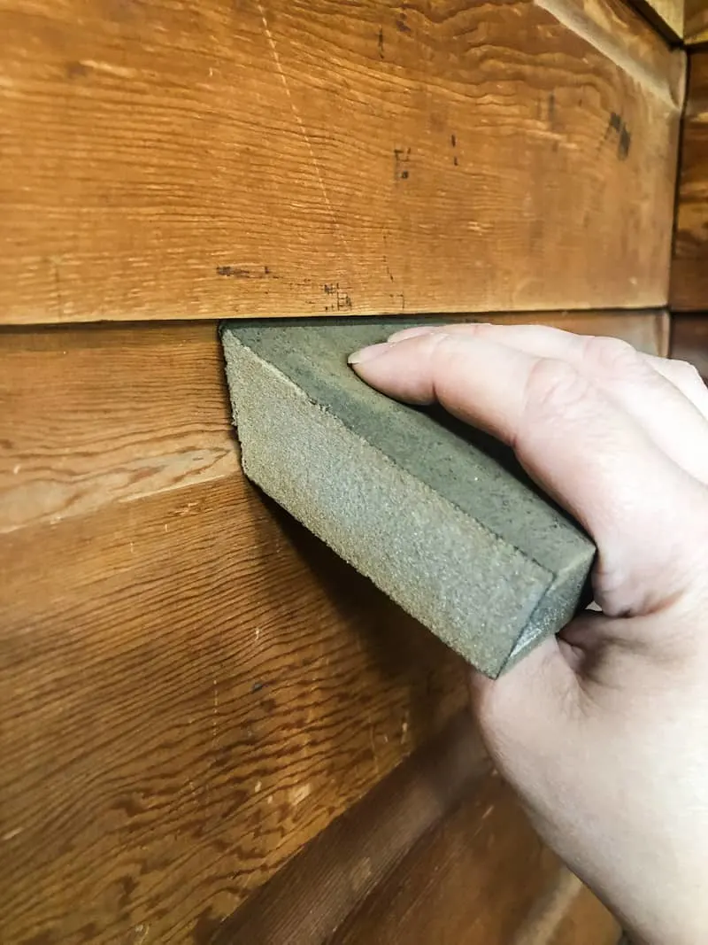 sanding wood paneling with angled edge of a sanding sponge