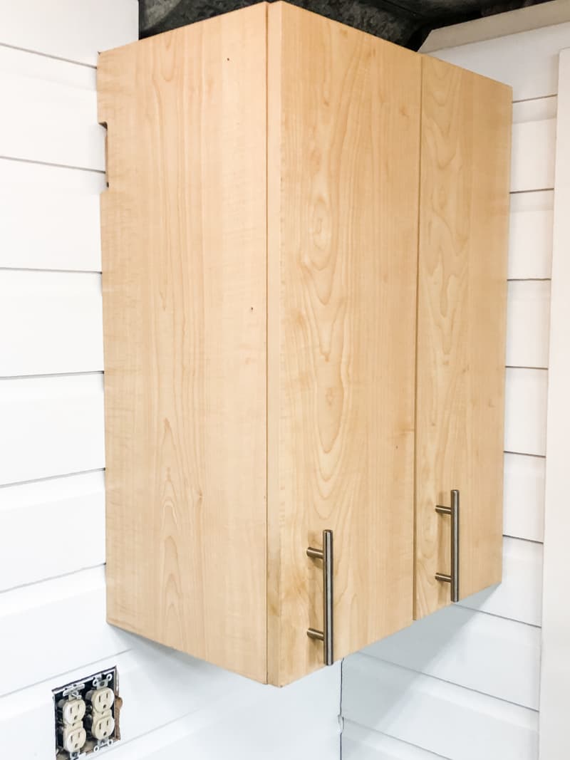 two birch wood cabinets hanging on white wood paneling