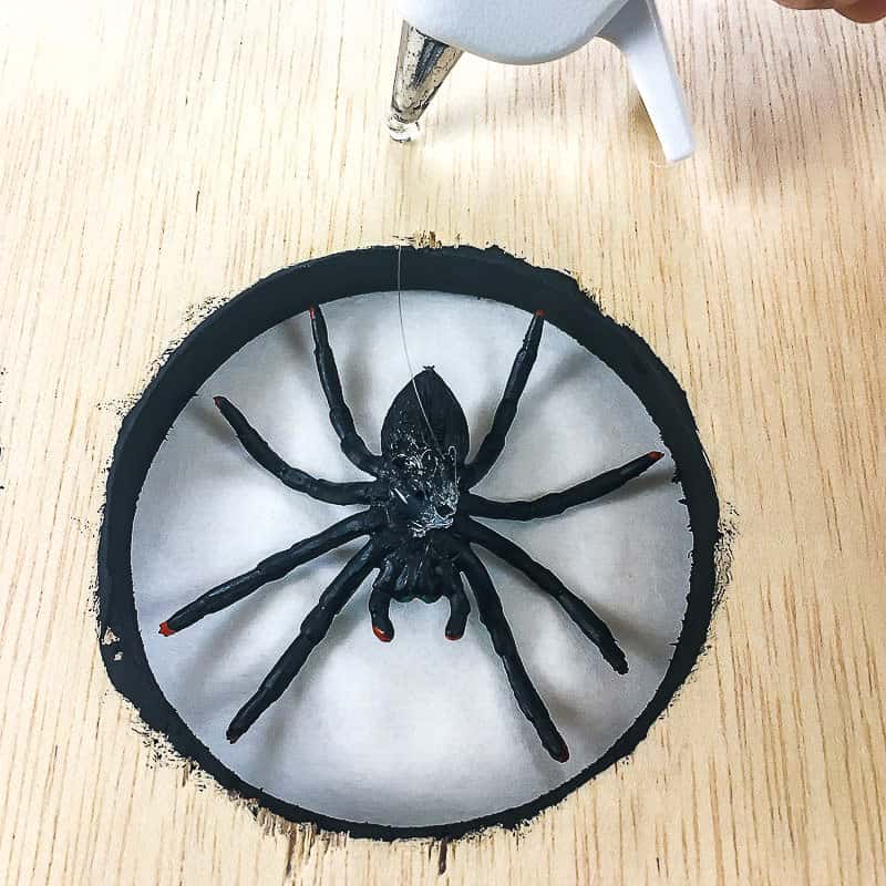 hot gluing plastic spider to Halloween spider decoration sign