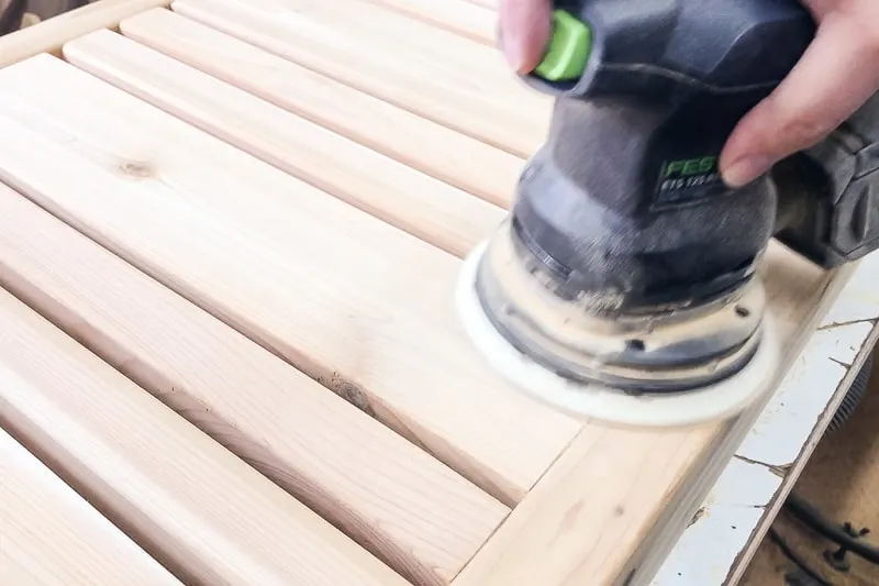 sanding slats of DIY coffee table with a random orbit sander
