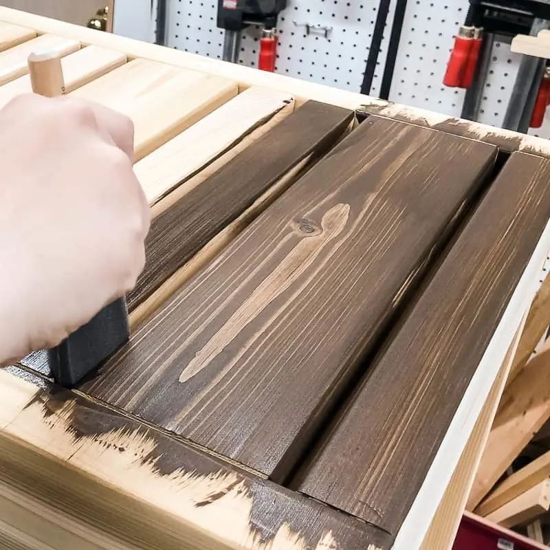 using a foam brush to apply stain to DIY outdoor coffee table