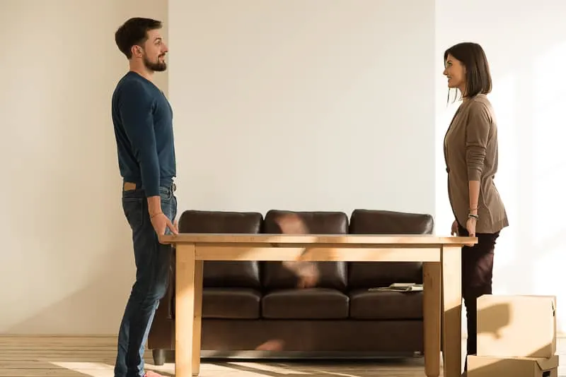 two people carrying a solid wood table