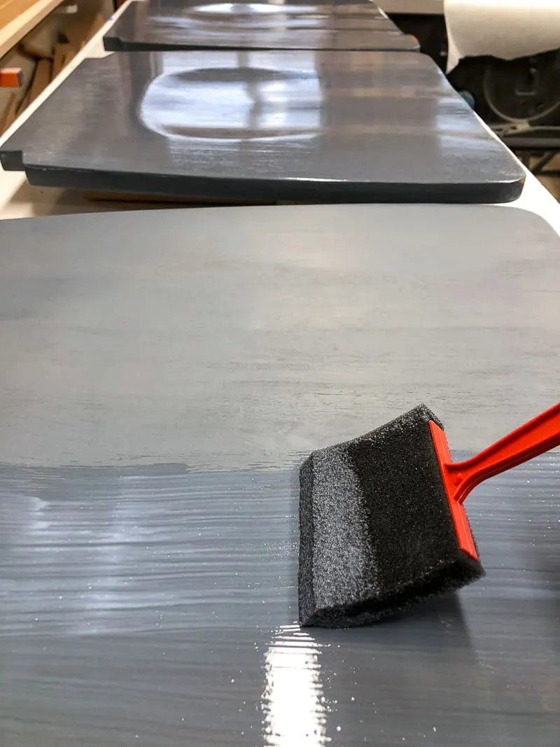 applying top coat to refinished chairs with a foam brush