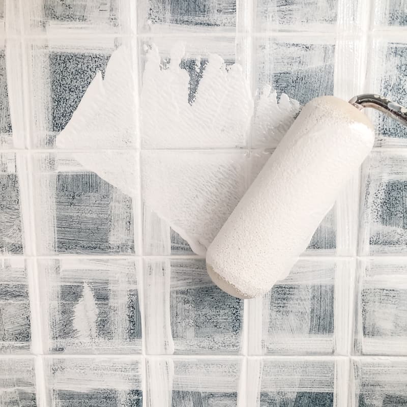 applying paint to backsplash tile with a roller