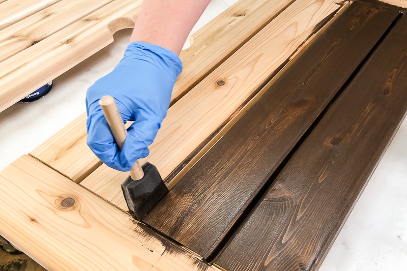 using a foam brush to stain between the slats of an umbrella stand table