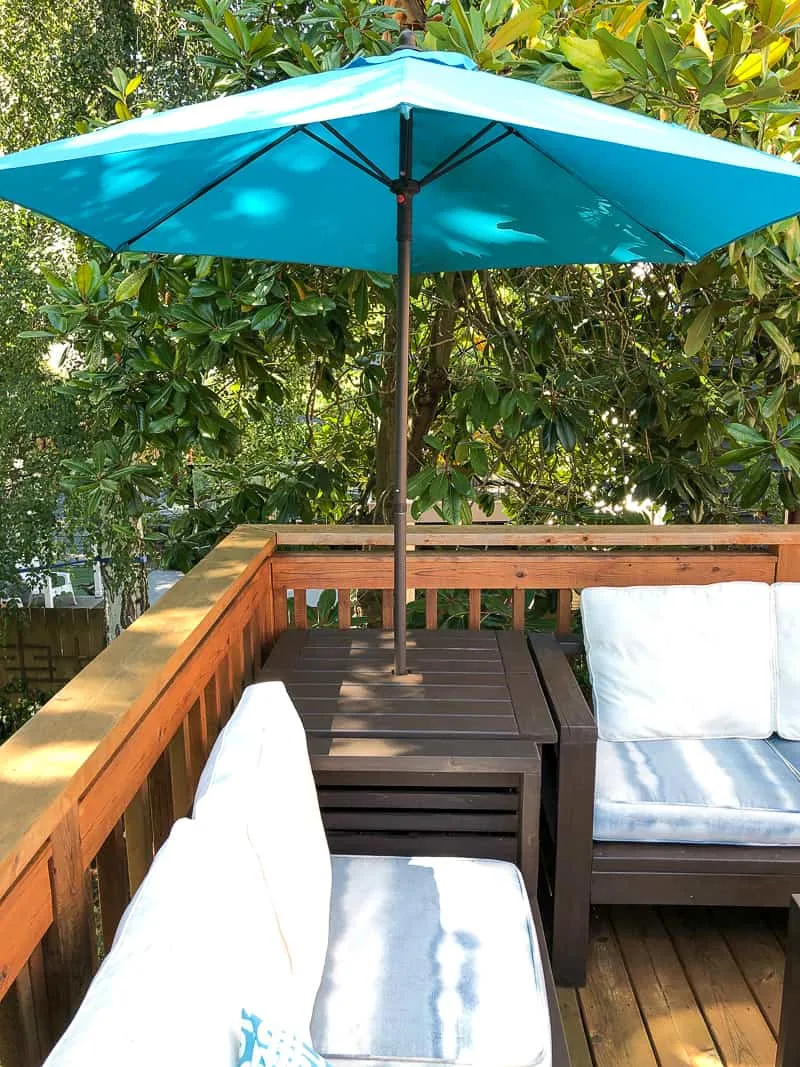umbrella stand table in corner between two outdoor sofas