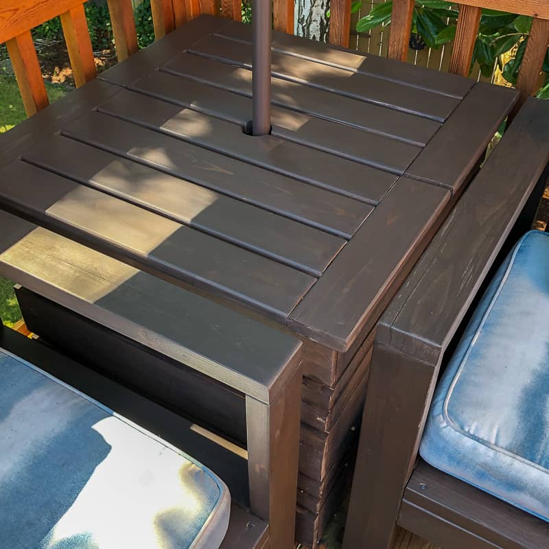 umbrella stand table in corner of deck between two outdoor sofas