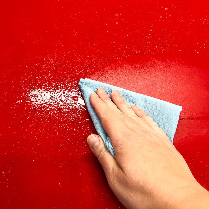 cleaning red cabinet door with windex
