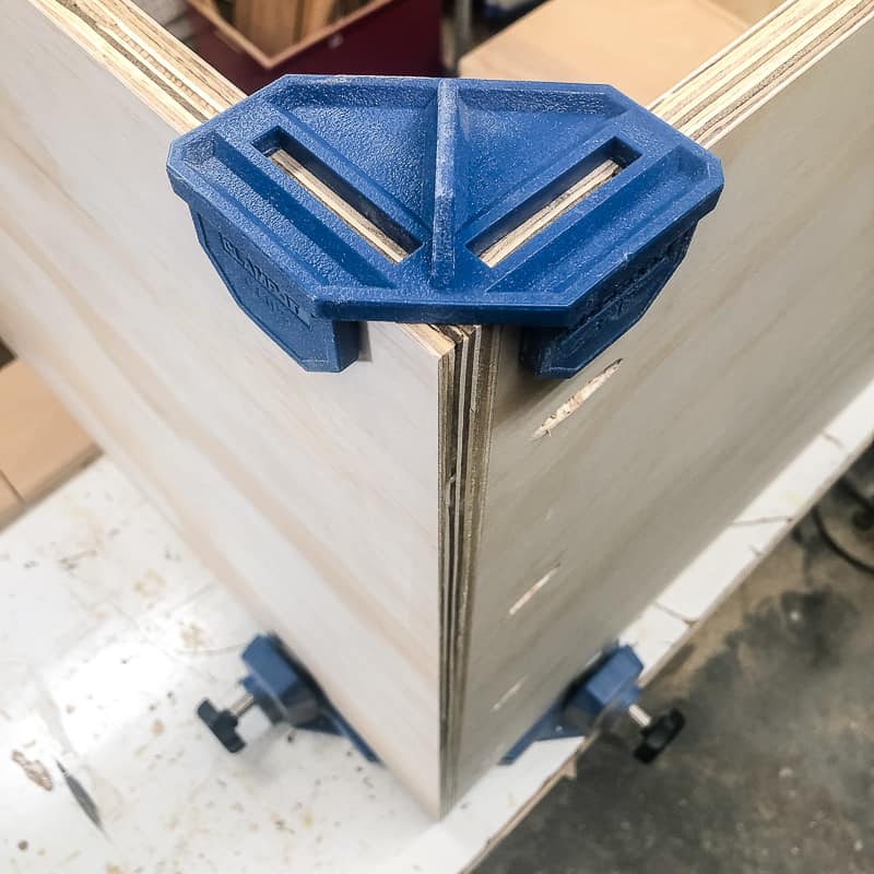 corner clamps holding plywood pieces of DIY workbench together