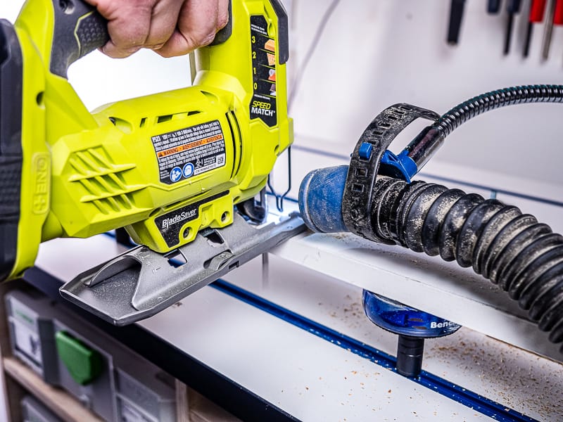 cutting with jigsaw on workbench with dust collector hose