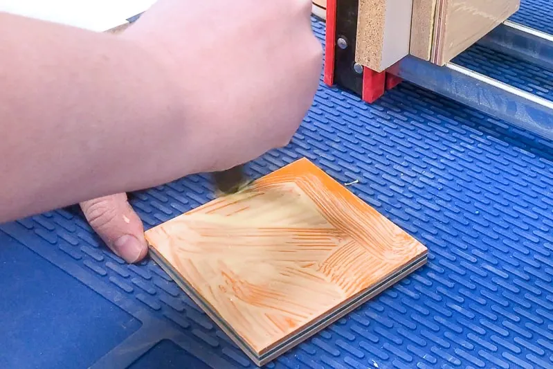 applying wood glue with a brush to orange skateboard veneer