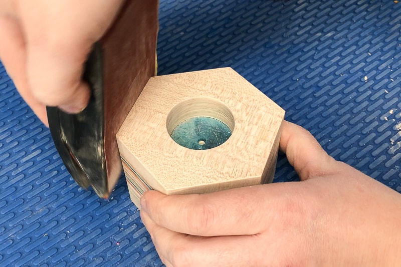 rounding over the edges of the DIY candle holder with a sanding block