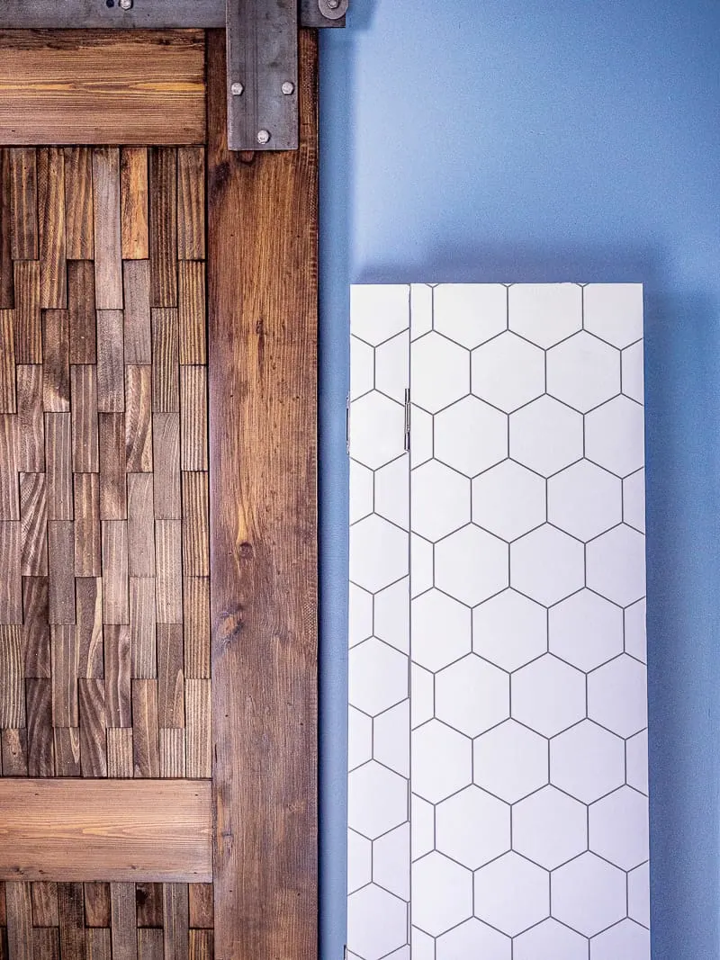 DIY room dividers folded up and leaning against the wall next to a sliding barn door