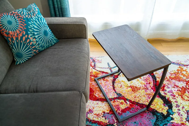 store bought laptop stand with fake wood top next to couch