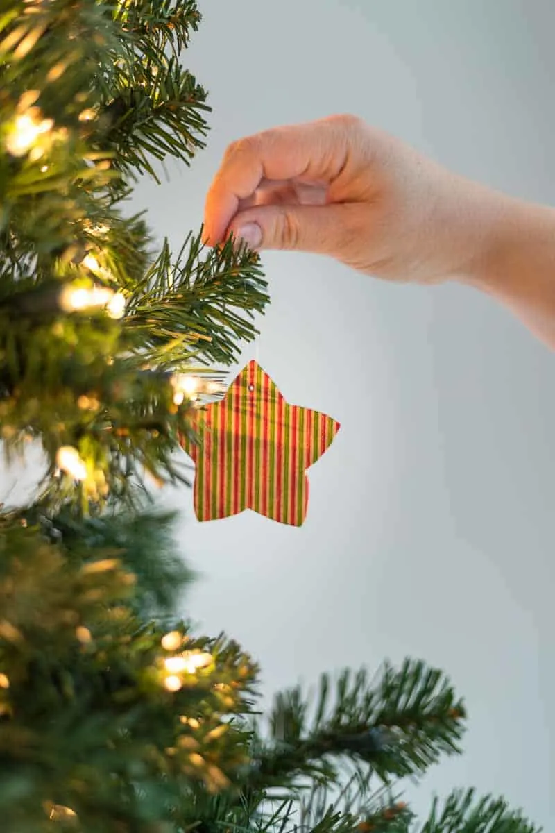 star shaped wooden ornament being hung from the Christmas tree