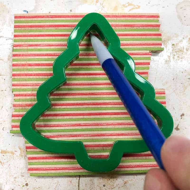 tracing Christmas tree cookie cutter shape onto wooden ornament