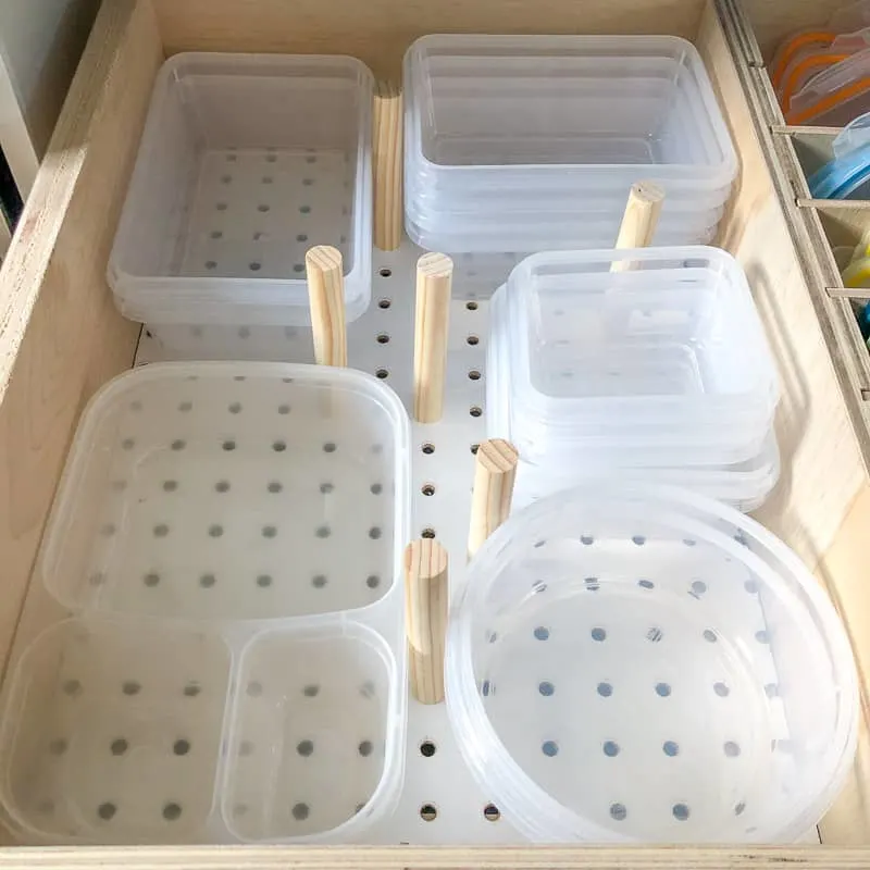 DIY drawer organizer with wooden pegs holding plastic containers in place