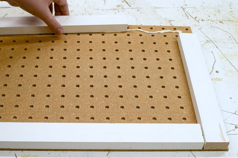 applying scrap wood to perimeter of pegboard