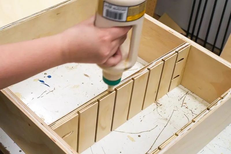 applying wood glue to bottom of the DIY drawer organizer