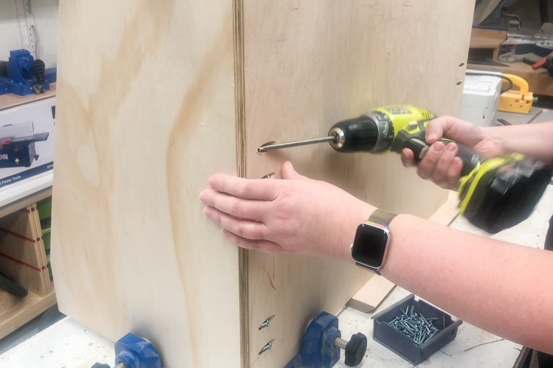 attaching the back of the DIY kids bookshelf to the sides with pocket hole screws