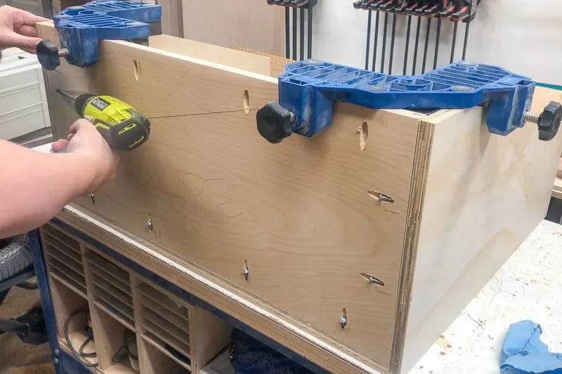 attaching the bottom of the DIY kids bookshelf to the sides and back with pocket hole screws