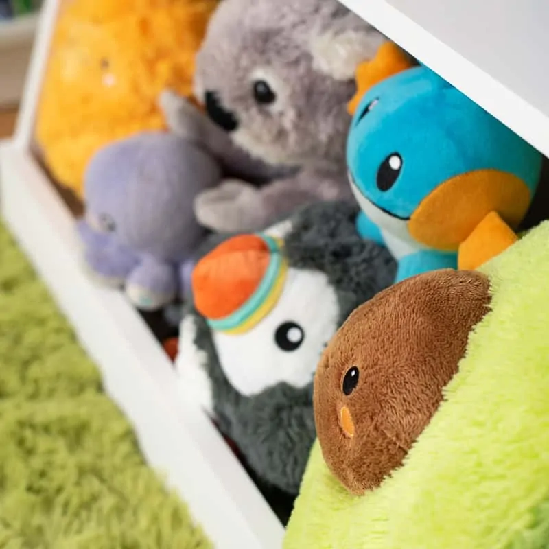 stuffed animals in bottom bin of DIY kids bookshelf with toy storage
