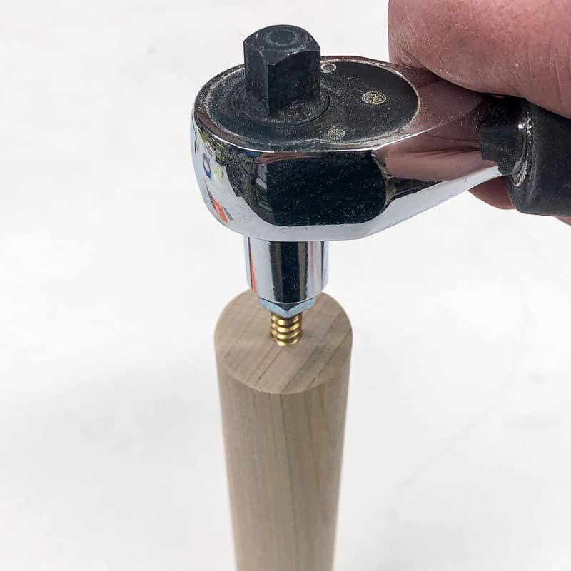 Use a socket wrench and locking nuts to install the hanger bolt into the end of the dowel or table leg.